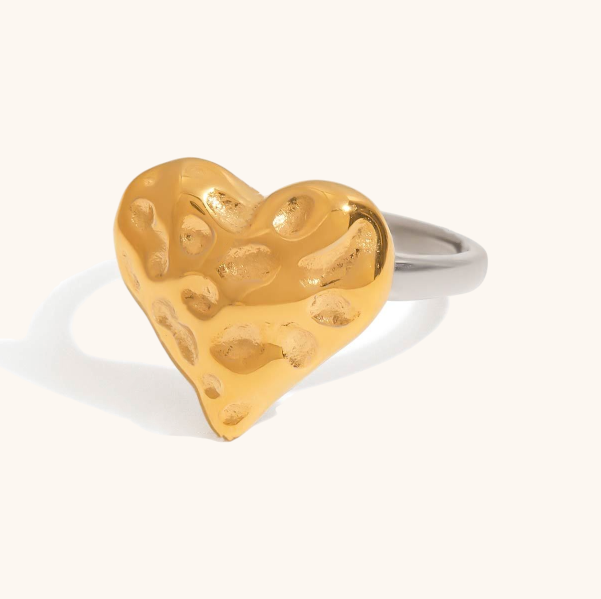 Gold and silver heart ring with hammered texture on white background