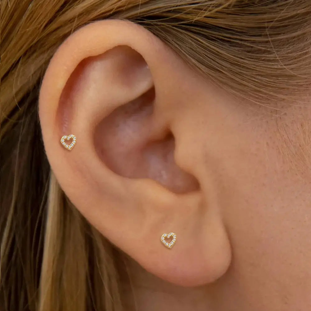 Model wearing 14k gold-plated heart-shaped zirconia stud earrings in her ear, showcasing a minimalist and modern style.
