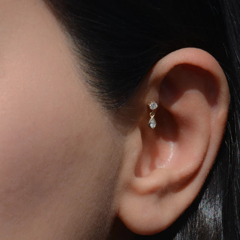 Close-up of a model wearing 14k gold teardrop zirconia stud earrings, showing their delicate shine