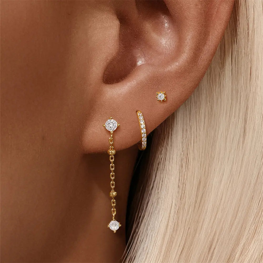 A model showcasing a 925 sterling silver 3-piece jewelry set with zirconia stones, featuring a stud earring, hoop earring, and a dangling earring with a chain.