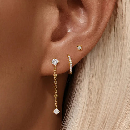 A model showcasing a 925 sterling silver 3-piece jewelry set with zirconia stones, featuring a stud earring, hoop earring, and a dangling earring with a chain.