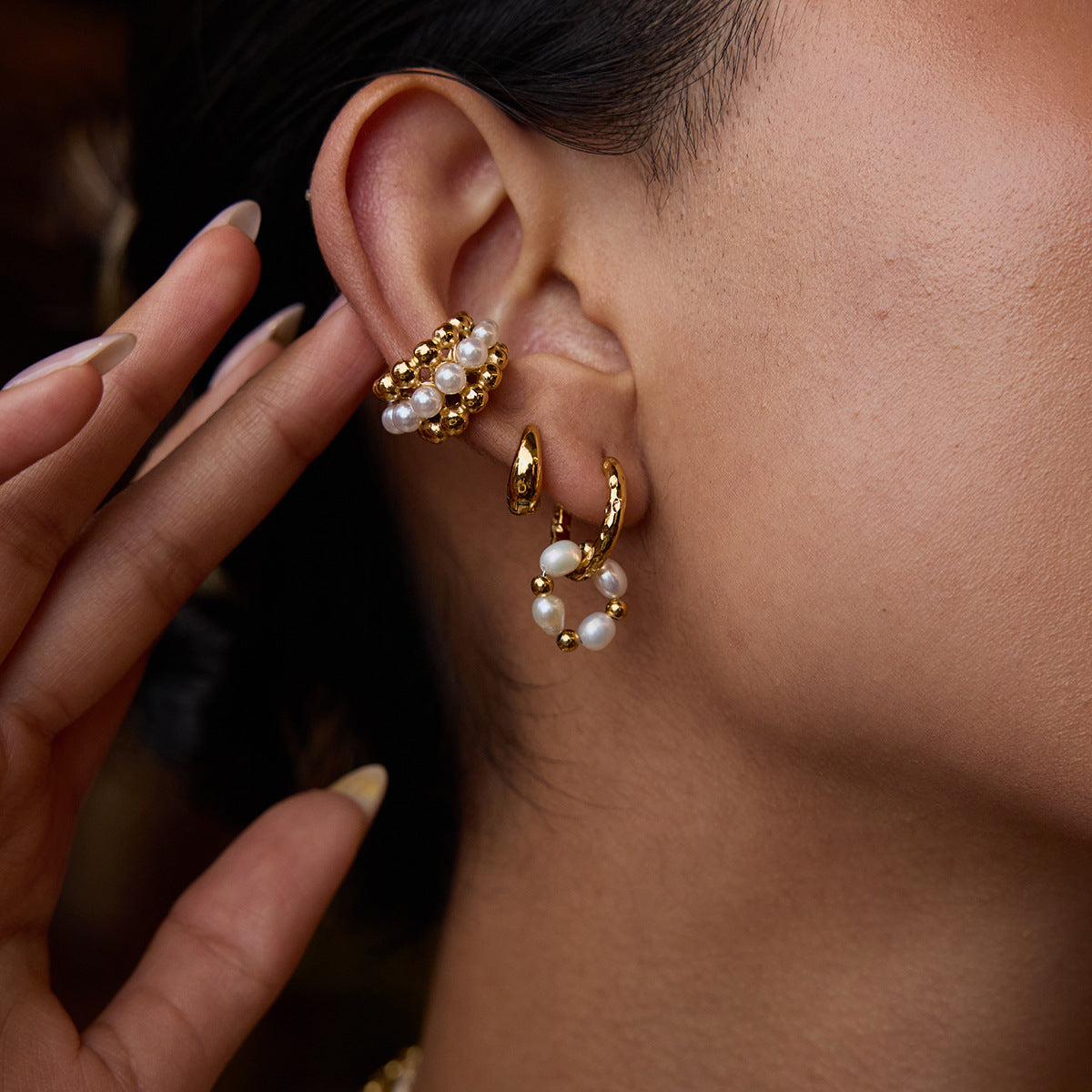 Stylish woman wearing layered gold and pearl earrings, perfect for trendy everyday looks or elegant dinners.