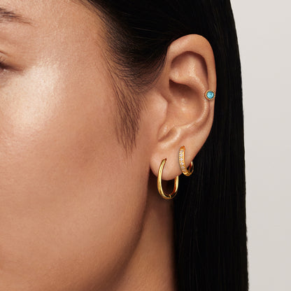 model wearing multi-hoop gold earrings with turquoise stud, stacked earring look