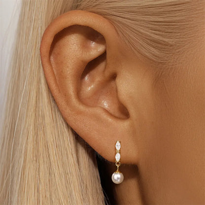 Close-up of gold-plated pearl drop earrings worn on a model, showcasing the marquise-cut zirconia detailing and timeless pearl charm.