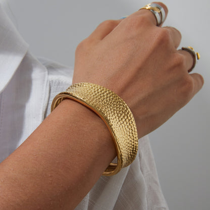 Model styling a wide gold cuff bracelet with white blouse and stacked rings, perfect for beachwear and daily looks