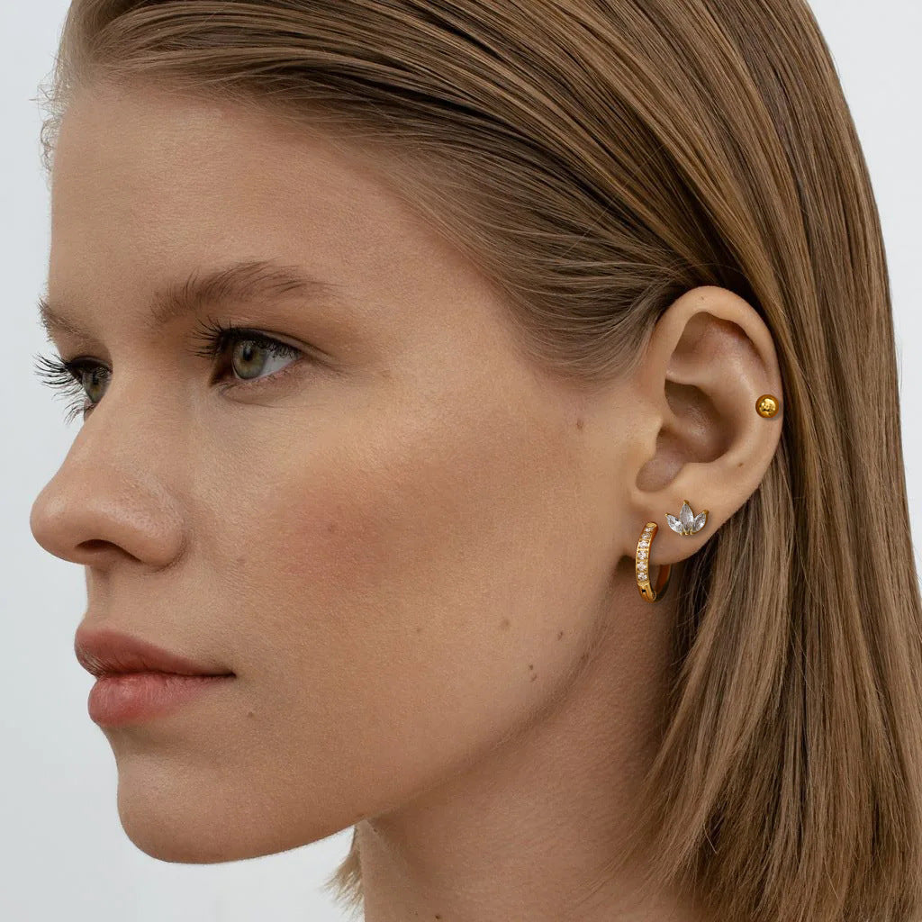  woman wearing gold earring set with hoops, studs and crystals