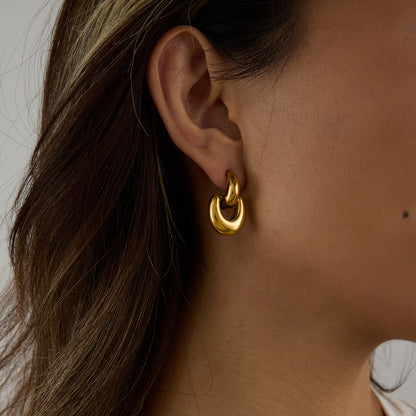 bold gold dangle earrings on woman’s ear