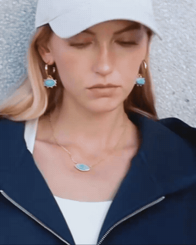 Statement turquoise drop earrings in gold hoops styled with casual streetwear outfit and cap.