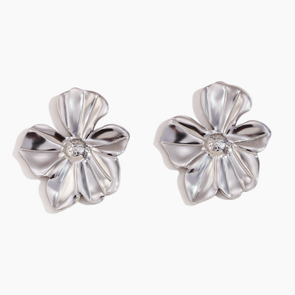 Pair of silver flower-shaped earrings with a central gemstone on a white background