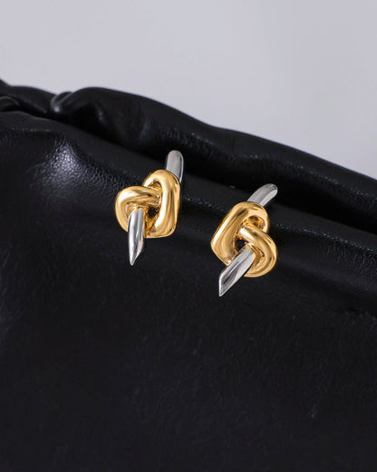 Gold and silver knot earrings on a black surface