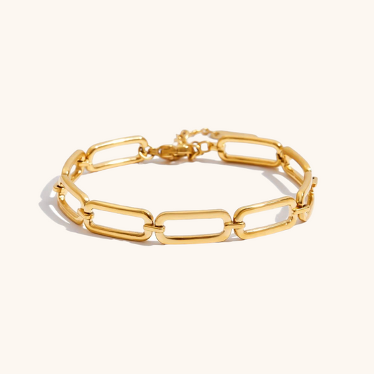 Close‑up of polished gold link chain bracelet showing smooth oval links on cream background