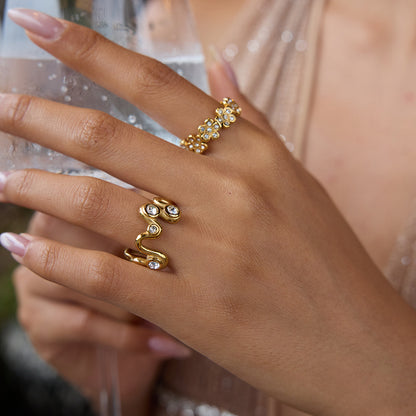 Gold wave crystal ring on finger, styled with glam outfit and holding drink
