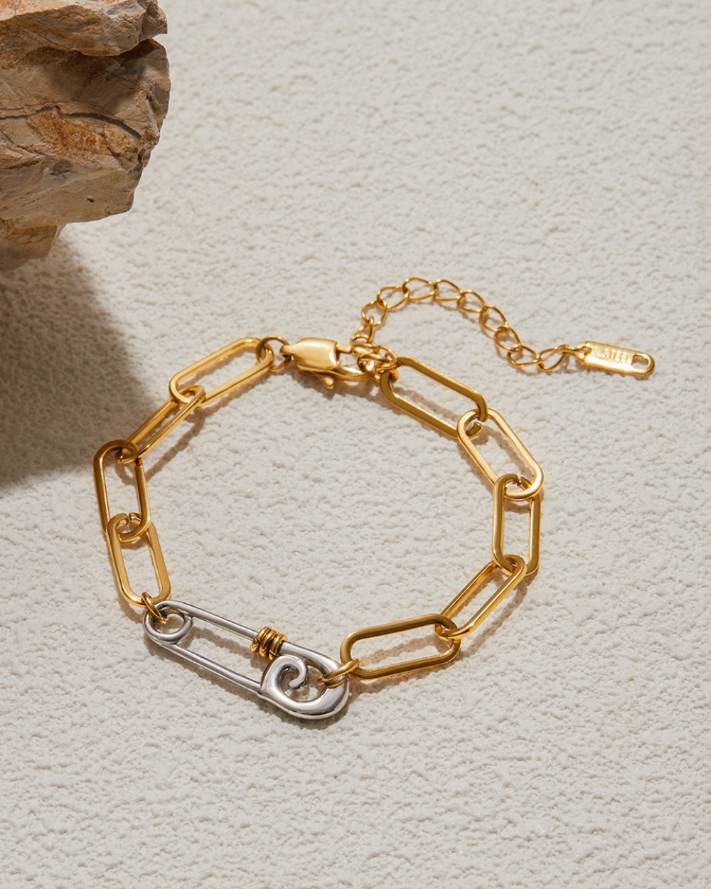 Gold chain bracelet with a unique clasp on a light gray background