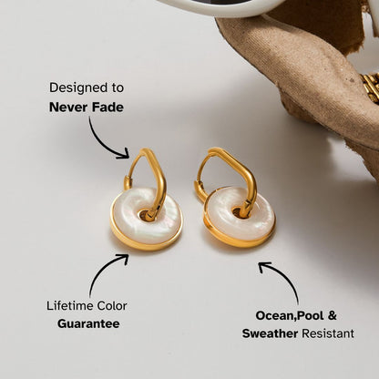 ocean-inspired white shell earrings on table with sunglasses