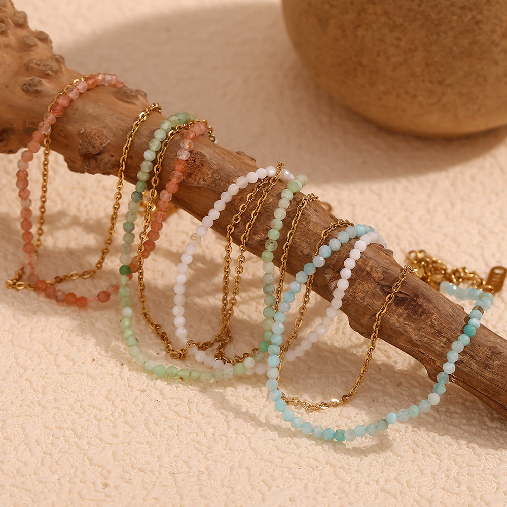 Stack of colorful faceted crystal and chain bracelets with layered styling.