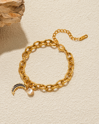 Gold chain bracelet with charms on a beige background