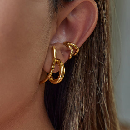 Golden bold hoops layered on model's ear against natural light