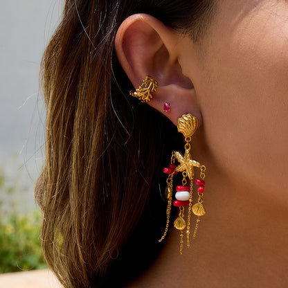 Model wearing gold starfish and red bead dangle earrings in the sun