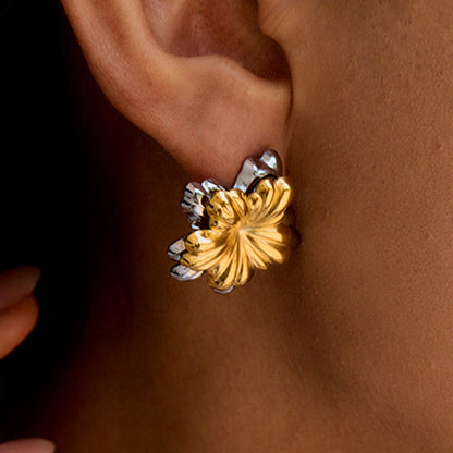 Model wearing thick gold-silver flower earrings with natural makeup