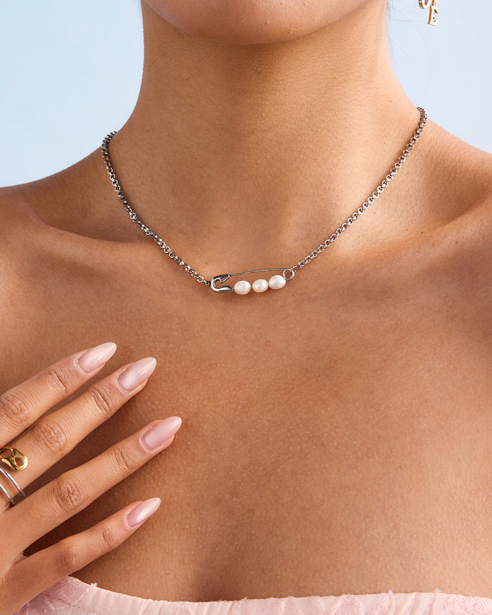Woman wearing silver safety pin necklace with freshwater pearls, styled with pink strapless dress