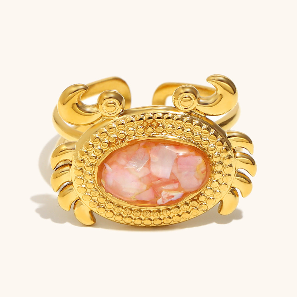 Shimmering pink resin shell crab ring with intricate gold claws and adjustable band.