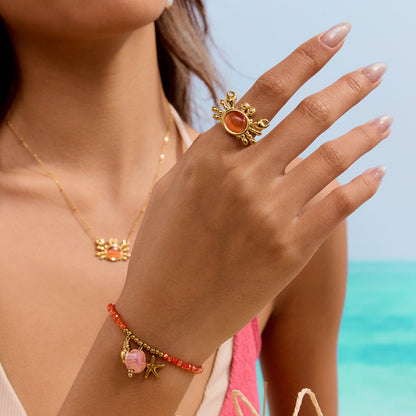Close-up of model’s hand wearing gold crab ring with cat eye gemstone
