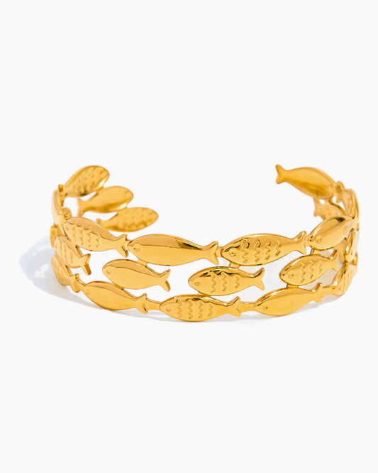 Gold bracelet with fish designs on a white background