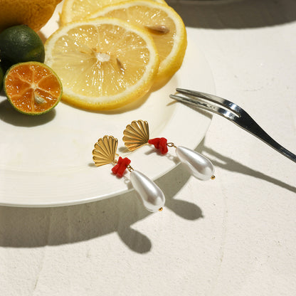 Bold summer earrings with gold shell tops, natural red coral, and glossy pearls styled with lemons