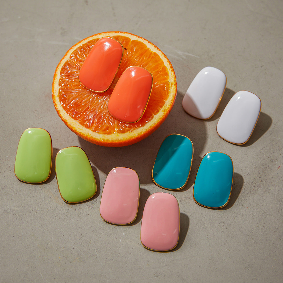 coral enamel earrings on orange background, colorful display set
