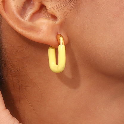 Flat lay of three pairs of pastel enamel U hoops on beige fabric, showing color variety