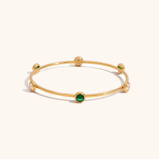 Flatlay of pearl-accented bangle on beige surface