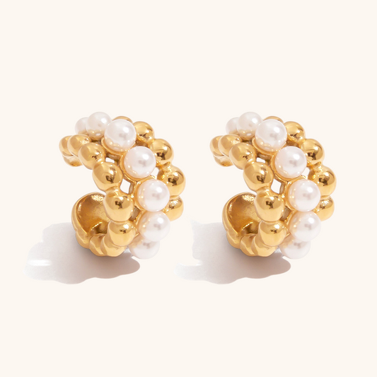 Close-up of chunky pearl ear cuffs with gold beaded texture on white background