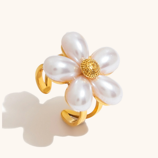 Bold gold daisy ring with teardrop pearls resting on stone surface