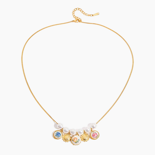 Gold necklace with colorful charms and pearl-like beads on a white background