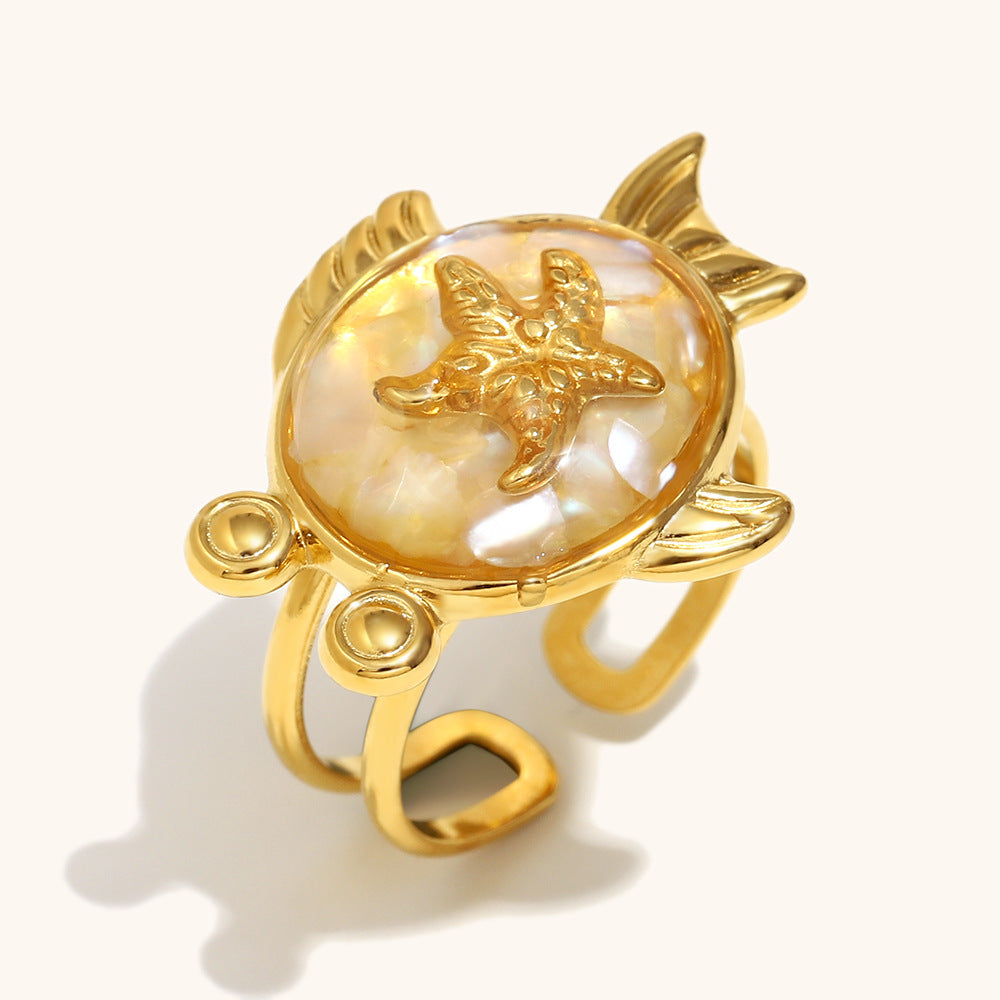 Golden starfish ring with creamy shell background and fish fins