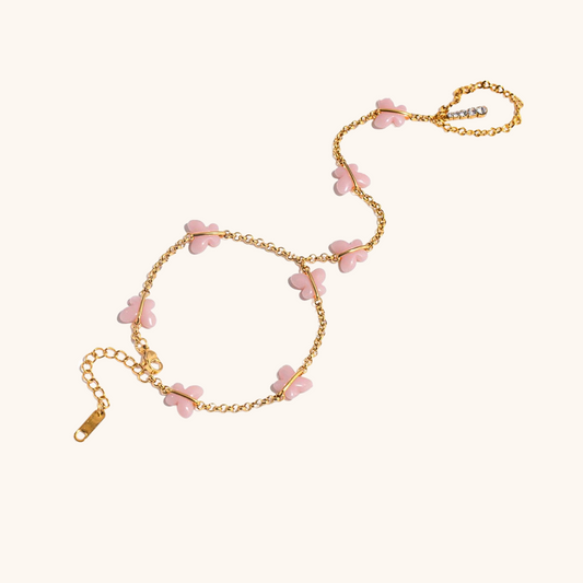 Close-up flat lay of pink butterfly jewelry with gold chain, romantic dainty aesthetic
