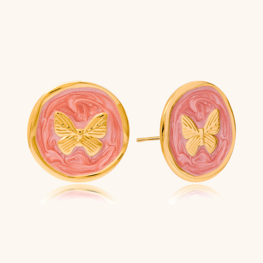 Round pink enamel earrings with golden butterfly detail on woman