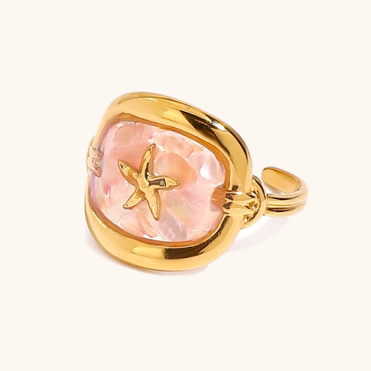 Close-up of pink shell ring with starfish motif in glossy gold frame