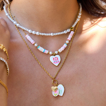 Model wearing layered gold and pastel necklaces with summer floral charms