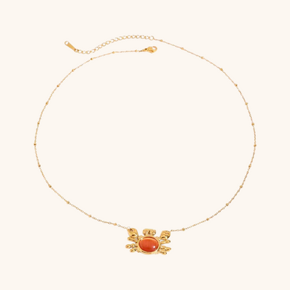 Flat lay of crab-shaped necklace and ring with seashells and citrus