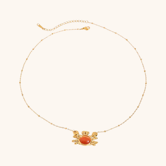 Flat lay of crab-shaped necklace and ring with seashells and citrus