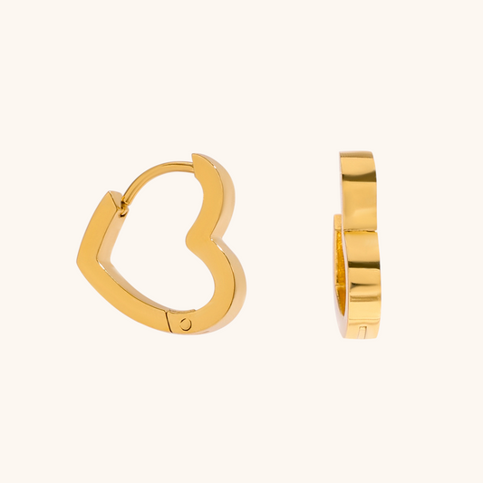 Close-up product shot of golden heart hoop earrings on cream background, minimalist style