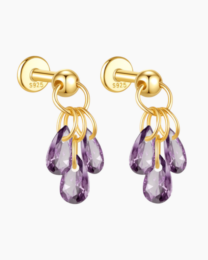 Gold earrings with purple teardrop-shaped gemstones on a white background