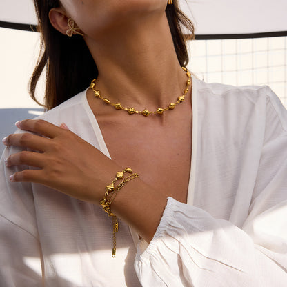 Rainbow gemstone golden brioche bead bracelet with sun charm, styled on model’s wrist in daytime outdoor shot