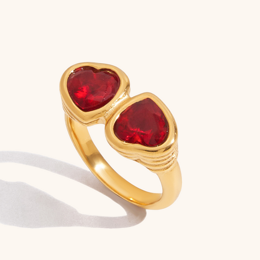 Studio close-up of gold double heart cocktail ring with red crystals