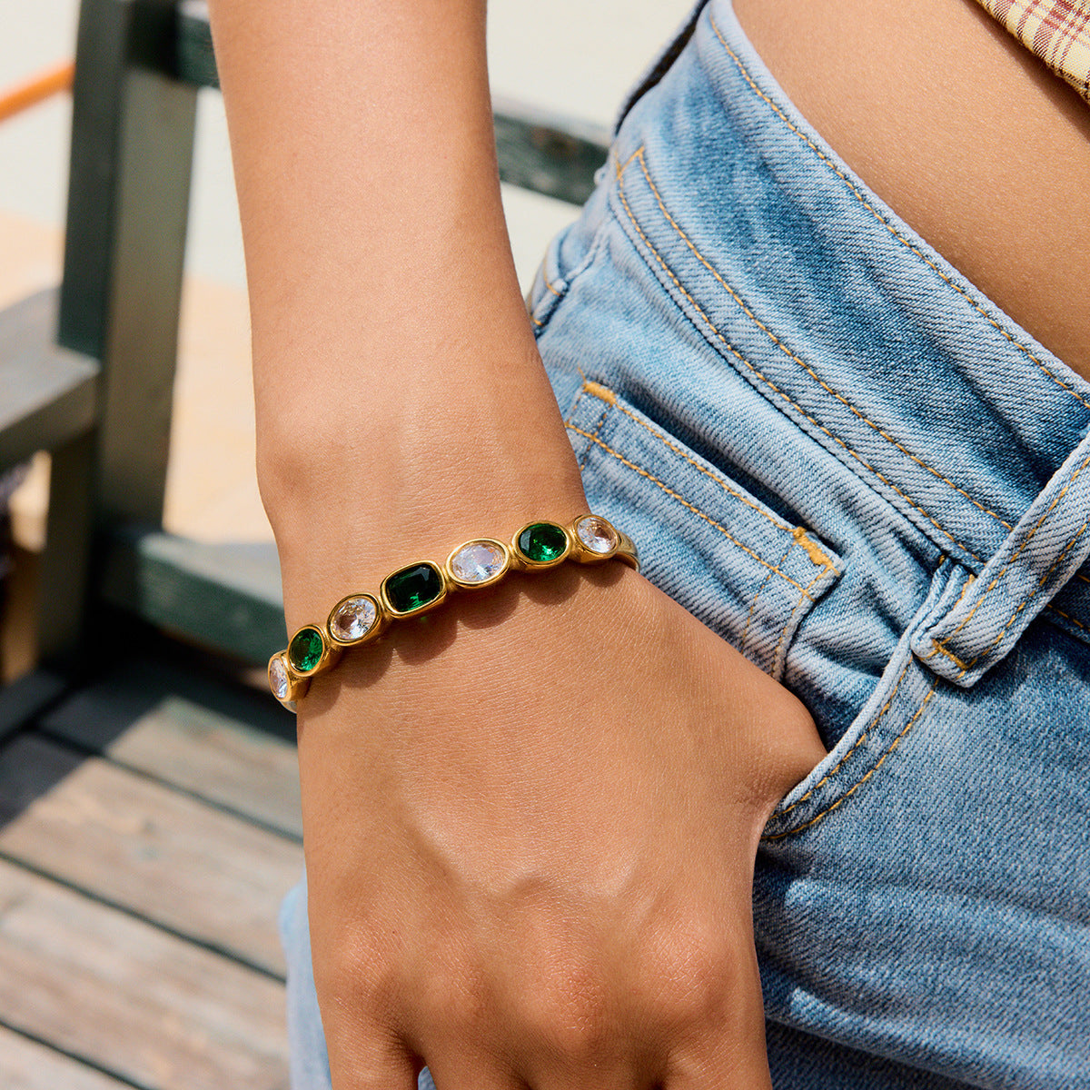 Green and crystal bracelet styled with denim shorts for a beach vacation vibe.