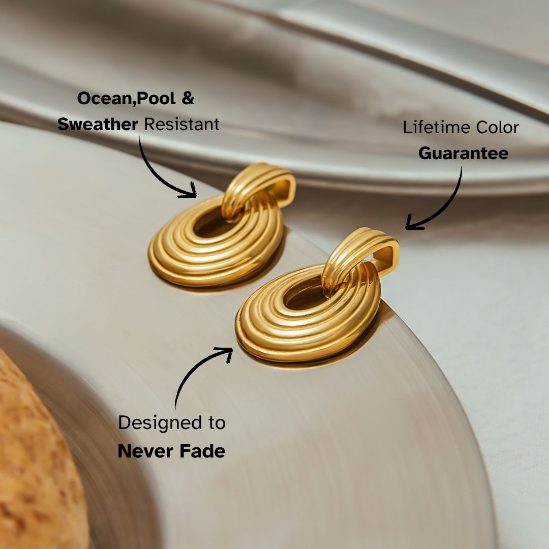 Close-up of gold drop-shaped earrings with layered ridges on a dish