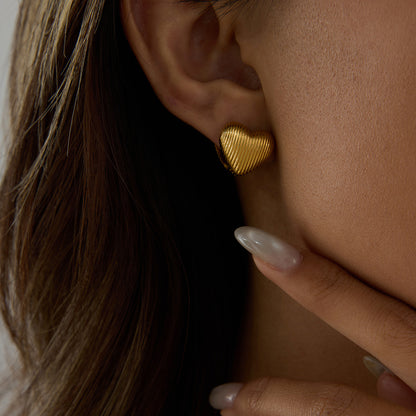 Model wearing vintage-inspired gold heart stud earring with ridged finish
