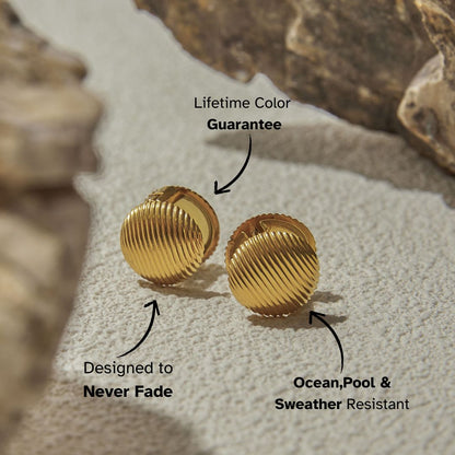 Vintage-style ribbed gold clip-on earrings on textured beige stone