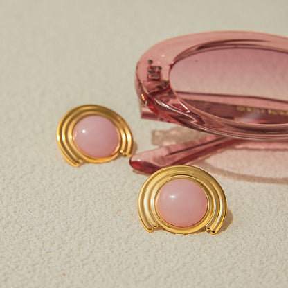 Trendy pink cat eye earrings styled with sunglasses, retro chic flat lay
